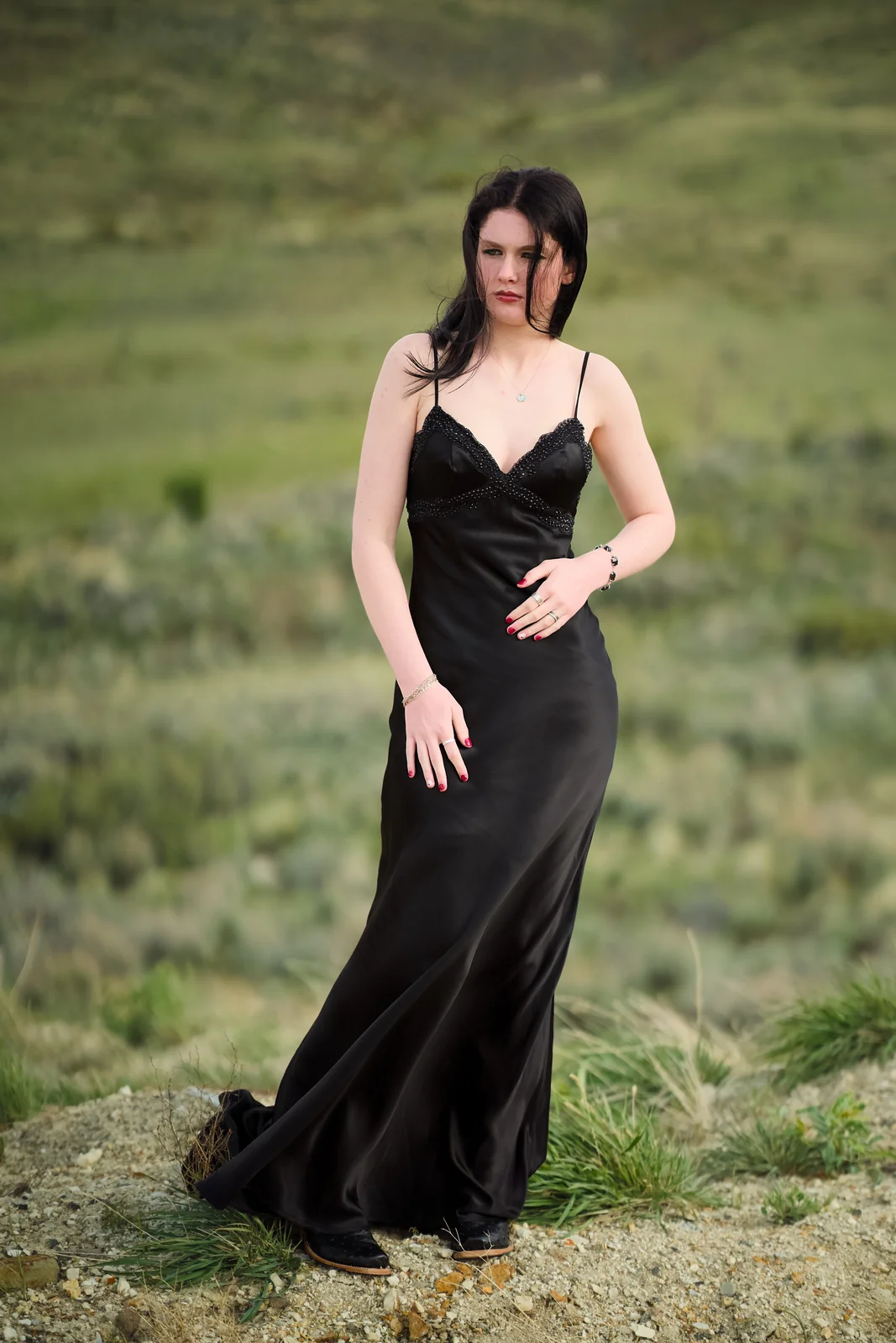 Woman in a black satin evening gown standing in a high desert landscape with sage brush