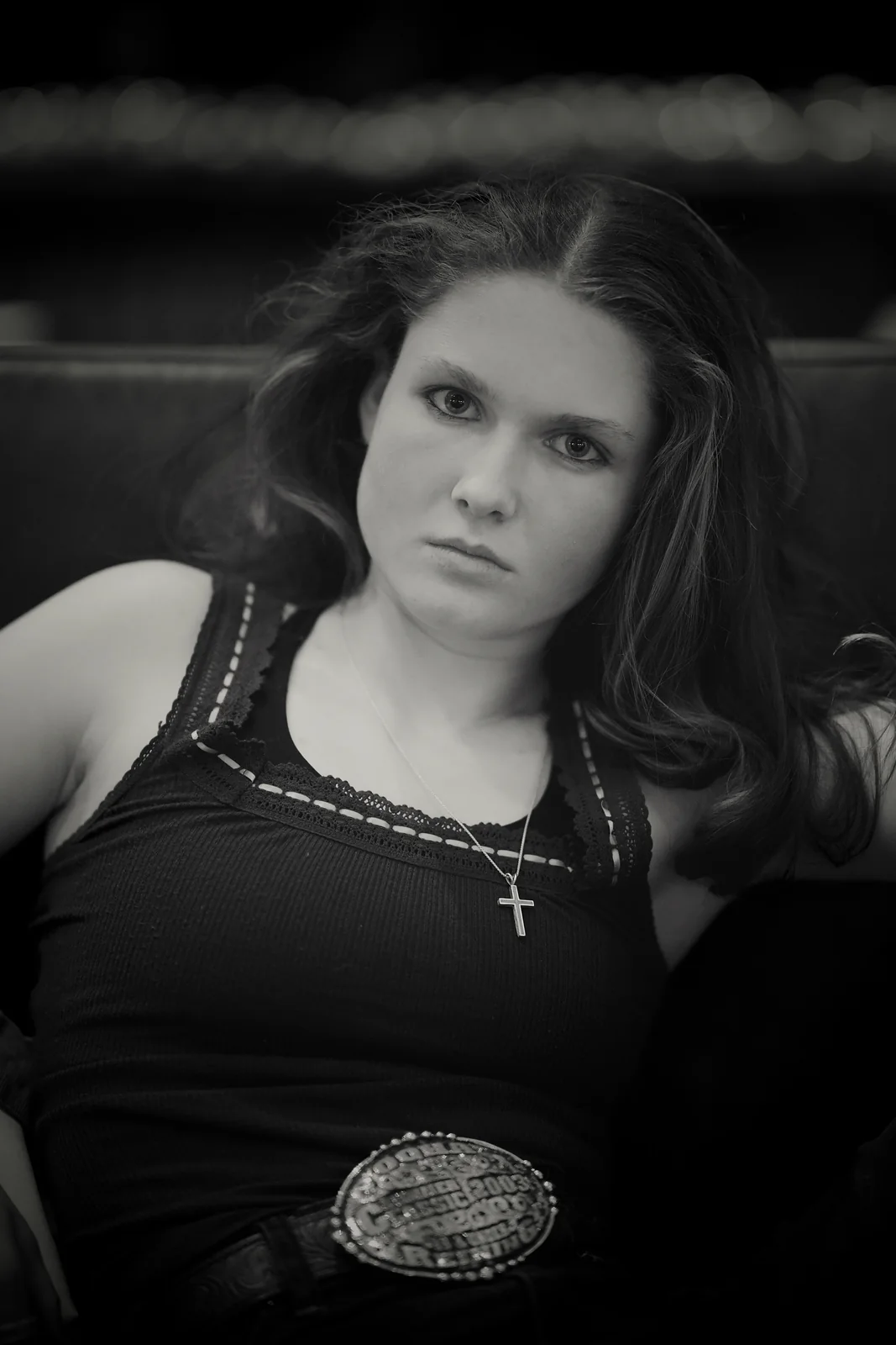 Close-up black and white portrait of a young woman with long dark hair and a cross necklace